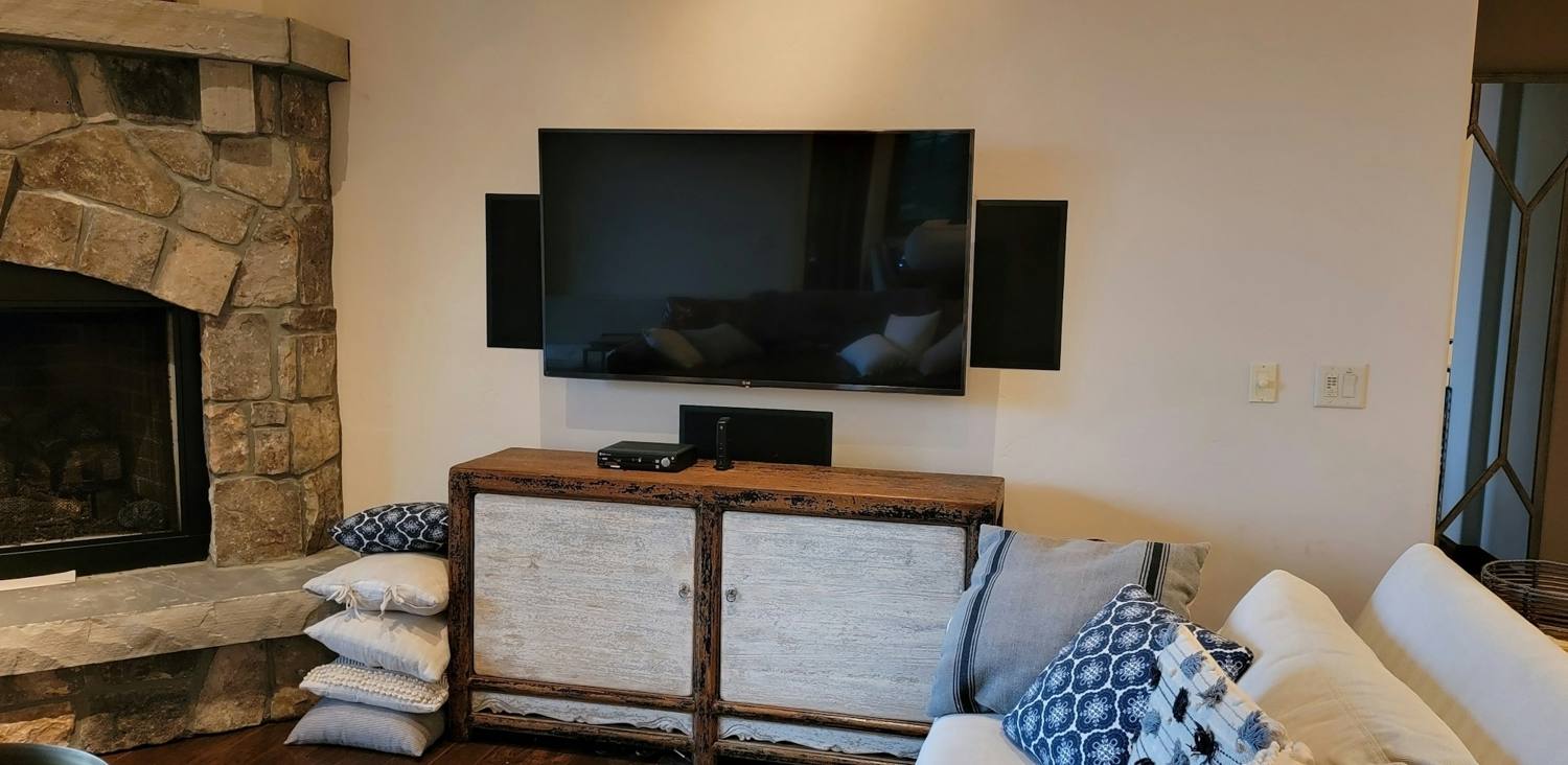 Finished lower-level living room with a stone fireplace and a wall-mounted television
