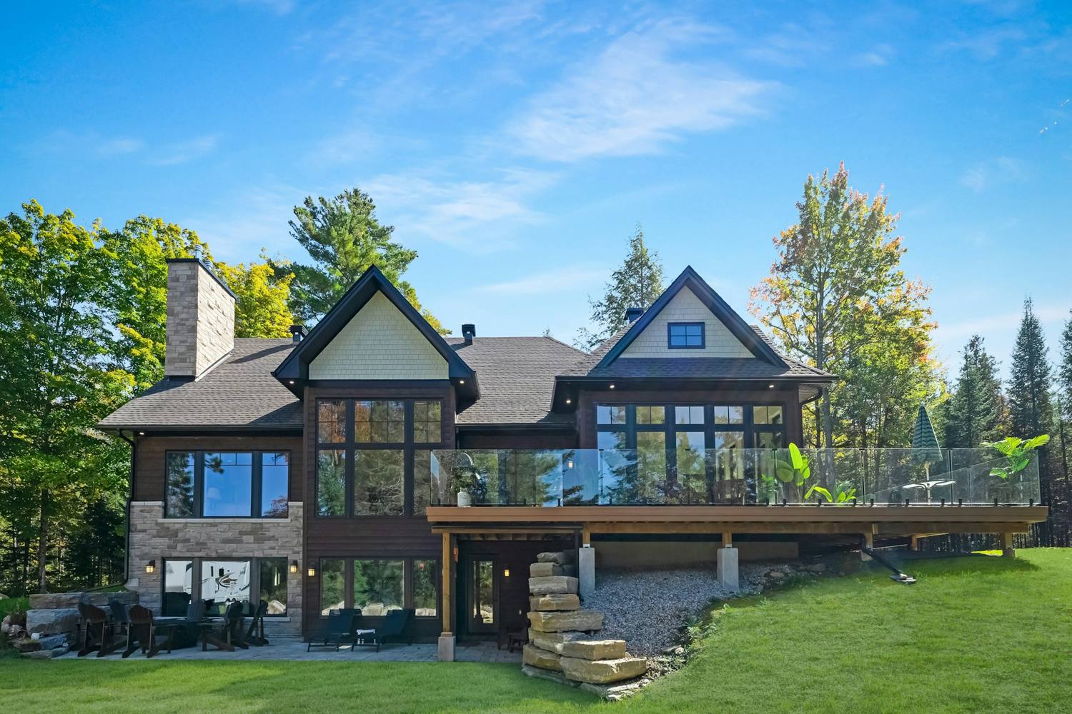 Raised deck with a glass railing on the back of a house on a sloped lot