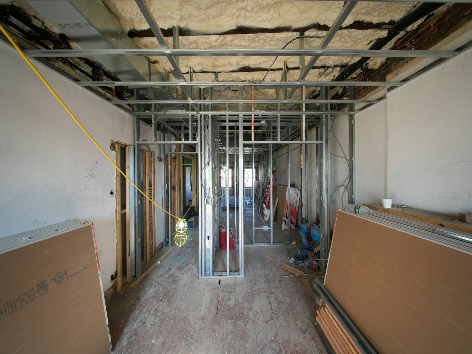 Interior stripped to steel studs with drywall sheets stacked against the walls