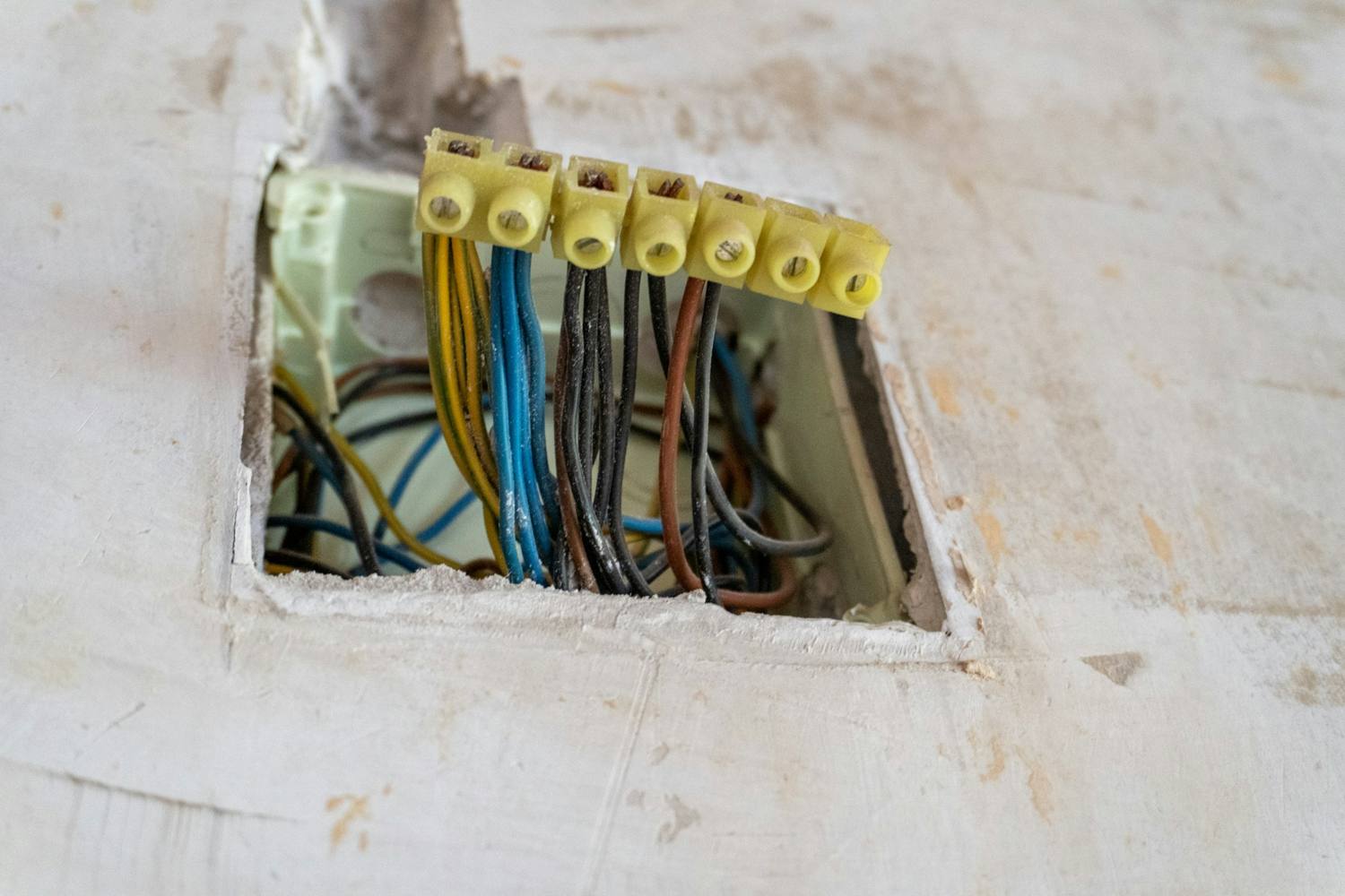 Wiring pulled out of an opening cut in a plaster wall