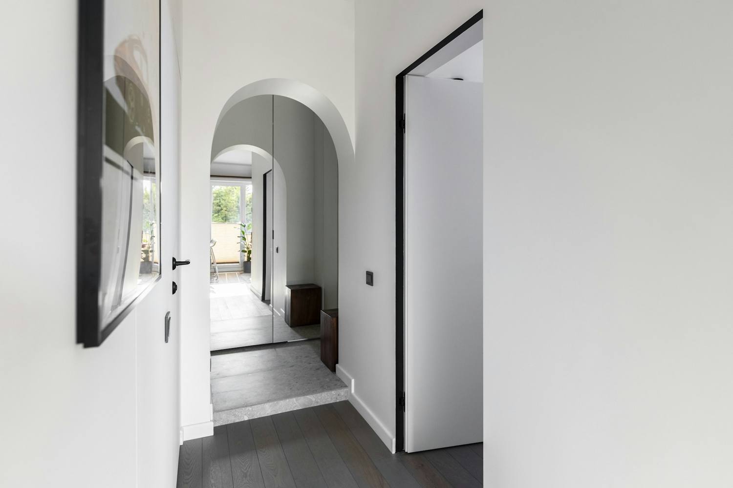 Hallway with an arched opening, painted trim, and a dark plank floor
