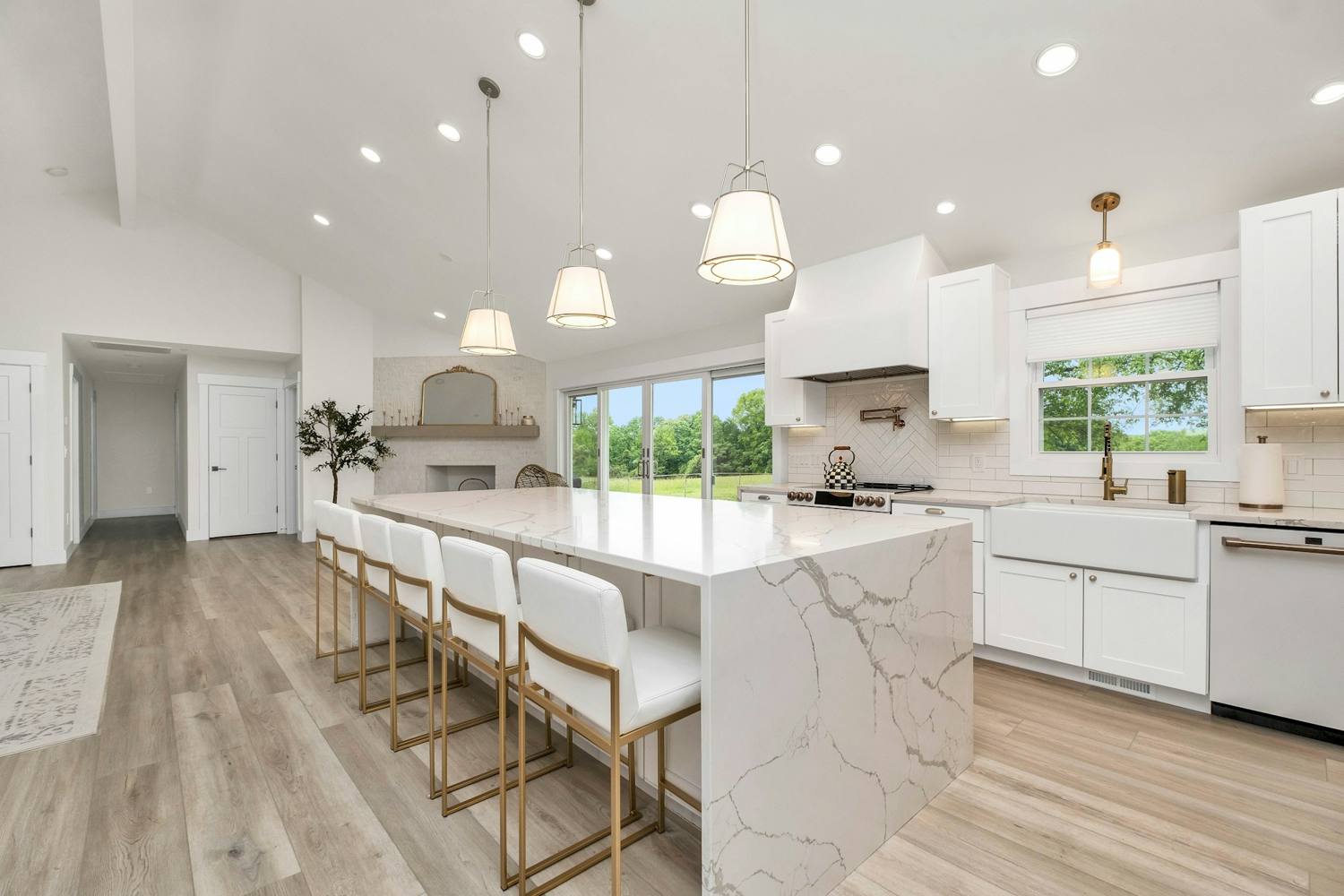 Remodeled kitchen with white cabinets, a quartz island, and pendant lights
